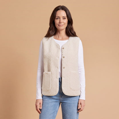 Woman wearing a beige teddy sherpa vest with small buttons and two patch pockets