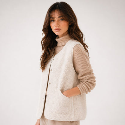 Side view of the beige teddy vest worn open with a hand in the patch pocket