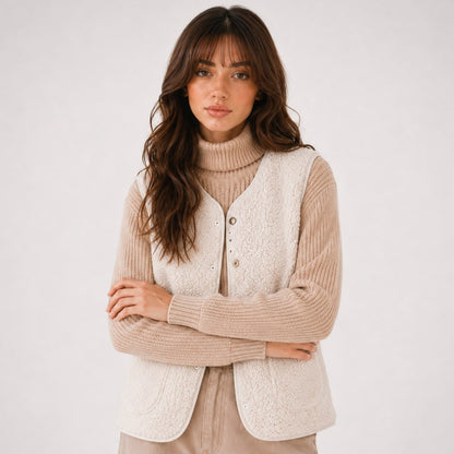 Front view of the beige teddy vest with round neckline worn over a ribbed sweater