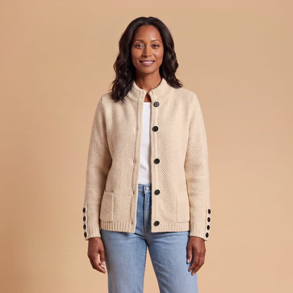 Woman wearing a beige textured knit button cardigan with a high stand collar and black buttons