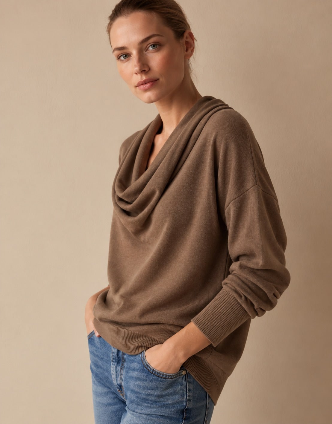 Brown cowl neck knit pullover sweater with hands in jeans pockets, side view 1