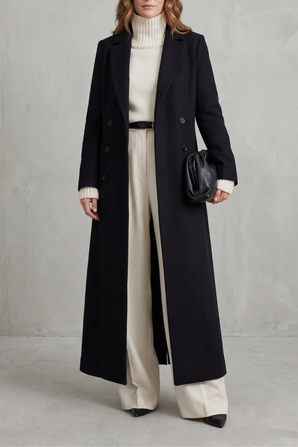 Black long tailored double-breasted coat worn with a cream turtleneck and wide trousers 1